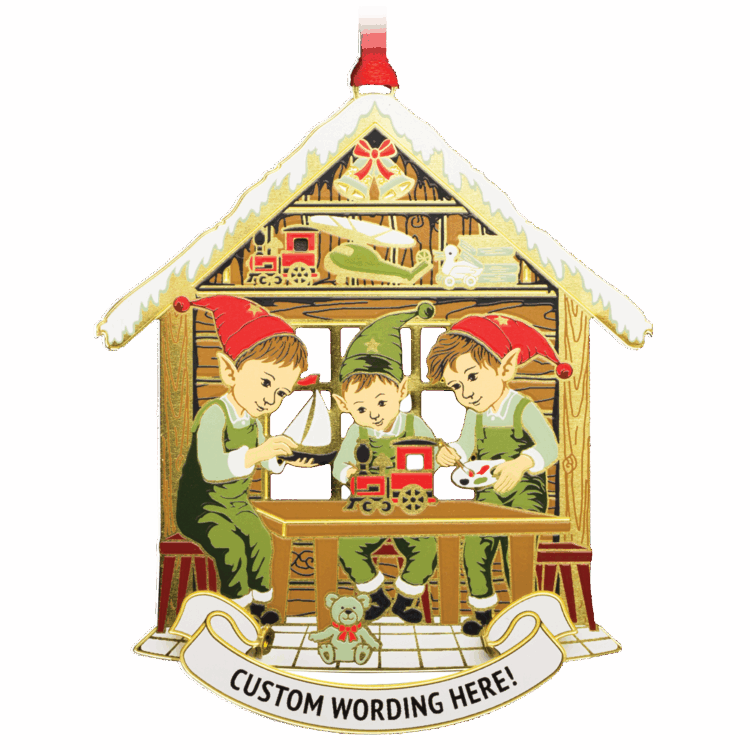 Ornament that features three elves dressed in green and red working on toys at a table in front of a brown house. White banner at bottom reads “CUSTOM WORDING HERE!” in black.